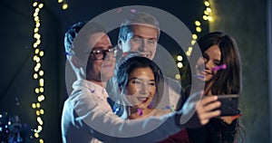 A group of young people smiling and throwing confetti, taking selfies for the new year, Christmas holiday