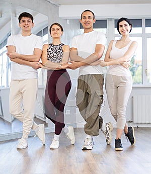 Group of young people stand in row holding hands, performing Irish folk dance.