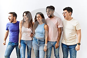 Group of young people standing together over isolated background angry and mad screaming frustrated and furious, shouting with