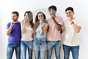 Group of young people standing together over isolated background with hand on chin thinking about question, pensive expression