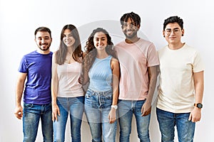 Group of young people standing together over isolated background with a happy and cool smile on face