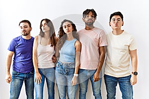 Group of young people standing together over isolated background looking at the camera blowing a kiss on air being lovely and sexy