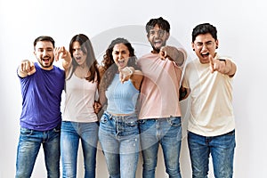 Group of young people standing together over isolated background pointing displeased and frustrated to the camera, angry and