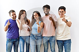 Group of young people standing together over isolated background pointing fingers to camera with happy and funny face