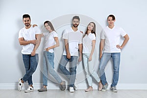 Group of young people in stylish jeans near wall