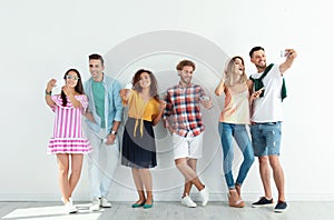 Group of young people taking selfie near wall