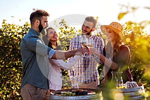 Group of young people tasting wine in winery near vineyard