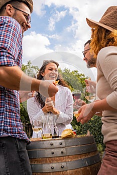 Group of young people tasting wine in winery near vineyard