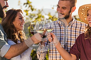 Group of young people tasting wine in winery near vineyard