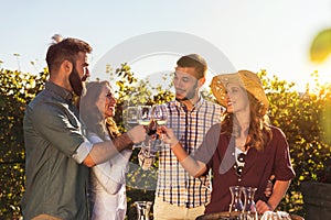 Group of young people tasting wine in winery near vineyard