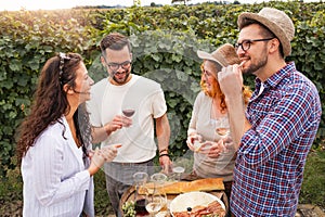 Group of young people tasting wine in winery near vineyard