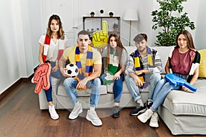 Group of young people watching football game wearing team scarf cheering game sitting on the sofa thinking attitude and sober