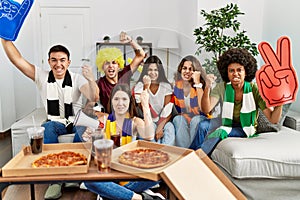 Group of young people wearing team scarf cheering football game annoyed and frustrated shouting with anger, yelling crazy with