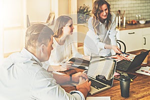 Group of young people working together.Man is using laptop,girls looking on screen of laptop,discussing business plan.