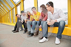 Group of young persons sit on footbridge