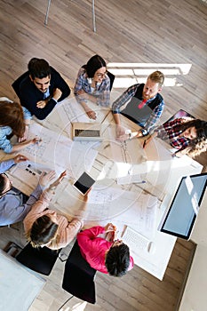 Group of young perspective architects looking at project papers