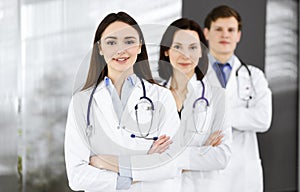 Group of young professional doctors is standing as a team with arms crossed in a hospital office and is ready to help