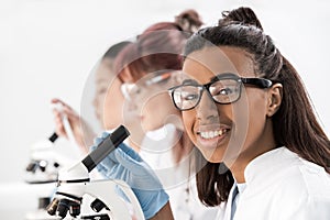 Group of young professional scientists working with microscopes in chemical lab