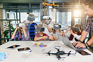 Group of young pupils of elementary school using virtual reality glasses during computer coding class.