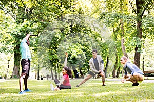 Group of young runners stretching and warming up in park.