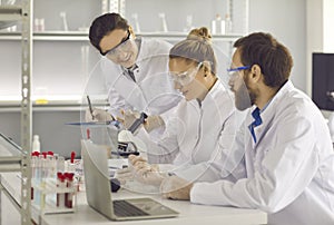 Group of young scientists working in a modern pharma or biotech science laboratory