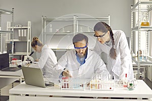 Group of young scientists working in modern pharma or biotech scientific laboratory