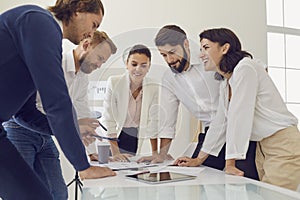 Group of young smiling office workers business people duscussing new project together in office