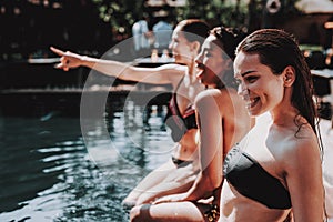 Group of Young Smiling Women Sitting at Poolside