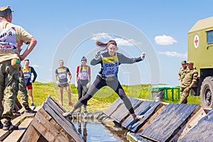 a group of young sport girl overcome the obstacles of the race of heroes competition. Text in Russian: Race of Heroes