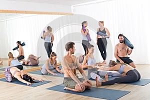 Group of young sporty attractive people in yoga studio, relaxing and socializing after hot yoga class. Healthy active