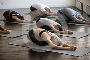 Group of young sporty people in Balasana pose