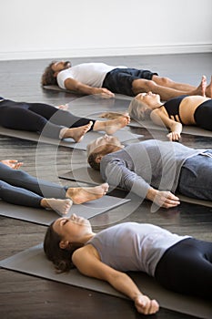 Group of young sporty people in Corpse pose