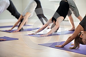 Group of young sporty people in Downward facing dog exercise