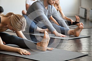 Group of young sporty people in Janu Sirsasana pose