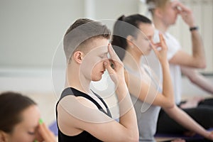 Group of young sporty people in nadi shodhana pranayama pose