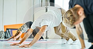 Group of young sporty people practicing yoga, together working out, indoor, studio.