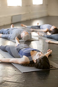 Group of young sporty people in Savasana exercise