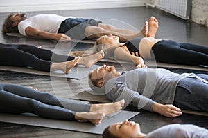 Group of young sporty people in Savasana pose