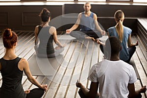 Group of young sporty people sitting in Sukhasana exercise