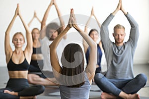 Group of young sporty people sitting in Sukhasana pose