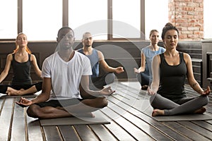 Group of young sporty people sitting in Sukhasana pose