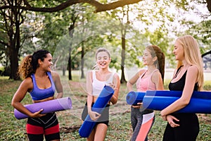Group of young sporty woman holding yoga mats and talking together at park,Happy and smiling,Relaxing time
