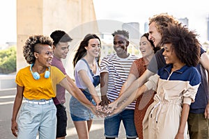 Group of young student friends with hands on stack showing international unity