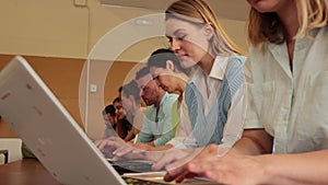 Group of young students searches for information on a laptop and writes it down in a copybooks, studying in a university