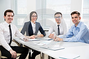 Group young successful business people sitting around the table in a modern office photo