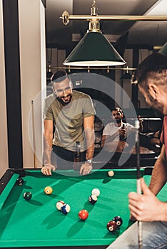 group of young successful handsome men playing in pool