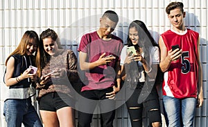 Group of young teenager friends chilling out together using smartphone social media concept