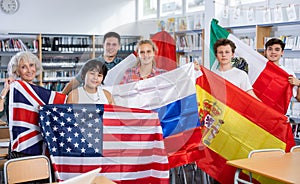 Group of young teenagers people holding international flags of many countries while studying