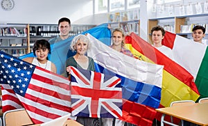 Group of young teenagers people holding international flags of many countries while studying