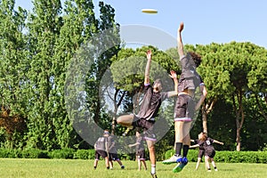 Group of young teenagers people in team wear playing a frisbee game in park oudoors. jumping man catch a frisbee to a teammate in